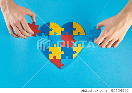 Autistic boy hands holding jigsaw puzzle heart shape. World Autism Awareness Day 99534992