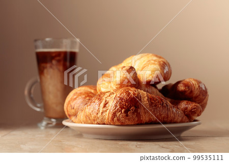 Freshly baked croissants and coffee with cream. 99535111