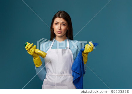 frowning woman cleaner apron with cleaning rag and detergent sprayer 99535258