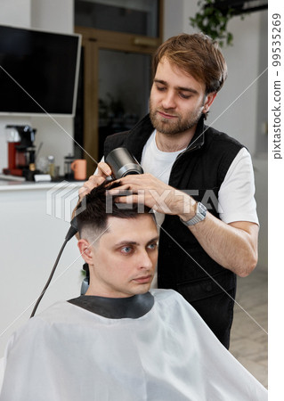 Professional hairdresser during work with man client with hair dryer Professional hairdresser during work with man client with hair dryer 99535269