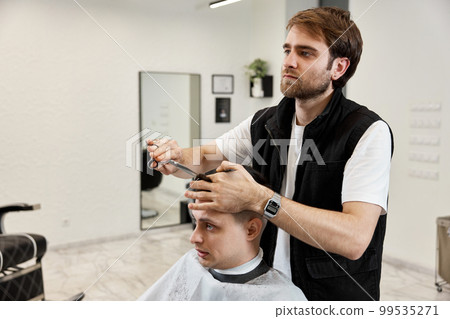 Professional hairdresser does haircut for caucasian bearded man Professional hairdresser does haircut for caucasian bearded man 99535271