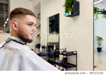 Handsome young man looks at his reflection in the mirror 99535282
