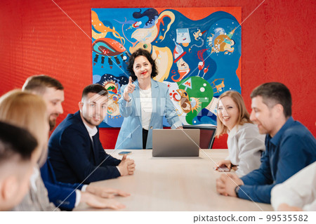 The female manager holds a meeting in a meeting room with large table. The female manager holds a meeting in a meeting room with large table. 99535582