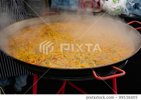 Process of cooking yellow paella in huge paella pan 99536805