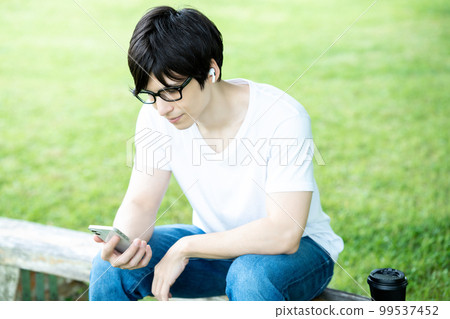 A man with glasses listening to smartphone music in a fresh green park A man with glasses listening to smartphone music in a fresh green park 99537452