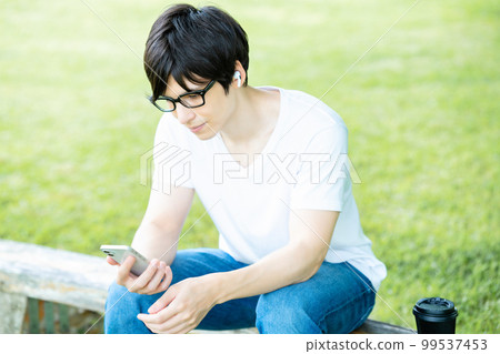 A man with glasses listening to smartphone music in a fresh green park A man with glasses listening to smartphone music in a fresh green park 99537453