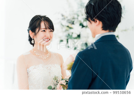 新娘和新郎在婚禮大廳用花束互相凝視（婚禮，新娘，情侶） 99538656