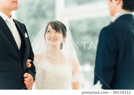 Bride/Bride's woman and father walking along a virgin road to the chapel where the groom waits at the wedding hall 99539312