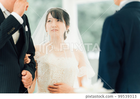 A bride and a crying father walk along a virgin road to the chapel where the groom waits at a wedding hall A bride and a crying father walk along a virgin road to the chapel where the groom waits at a wedding hall 99539313