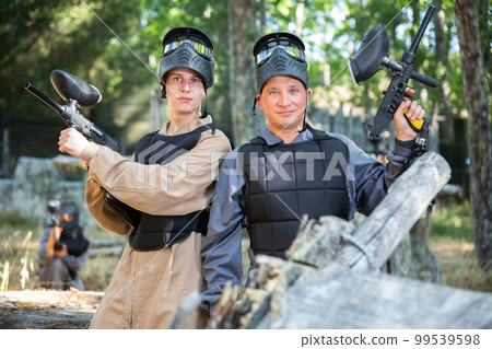 Portrait of positive man and teenage boy paintball players 99539598