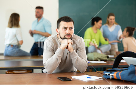 Portrait of a thoughtful student sitting at a table in an auditorium Portrait of a thoughtful student sitting at a table in an auditorium 99539669