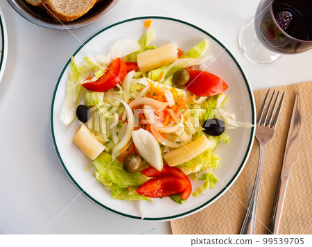Fresh mixed salad with lettuce, cabbage, carrots, onions, tomatoes, olives. Spanish dish ensalada variada 99539705