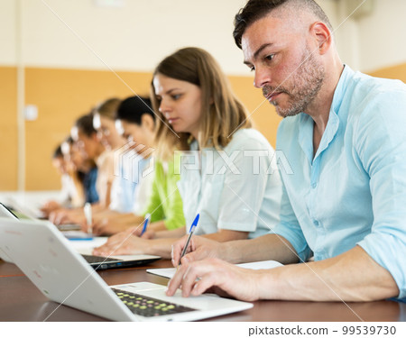 Portrait of a student guy, studying on a laptop and writing a synopsis 99539730
