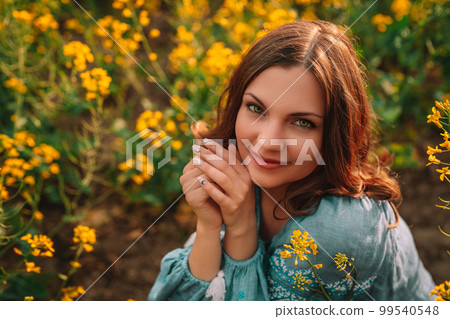 Smiling ukrainian woman in embroidery vyshyvanka blouse in yellow canola field.  99540548