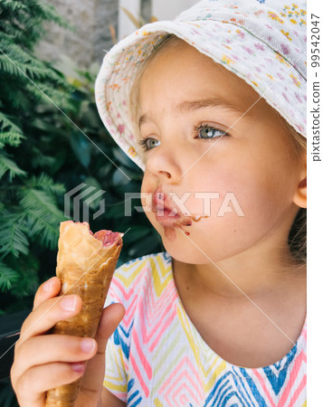 Little girl holding a waffle cone with ice cream in her hand 99542047