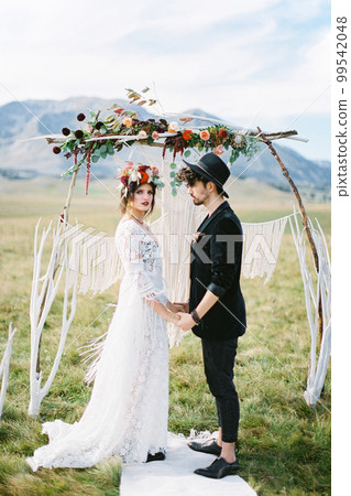 Bride and groom holding hands near the wedding arch 99542048