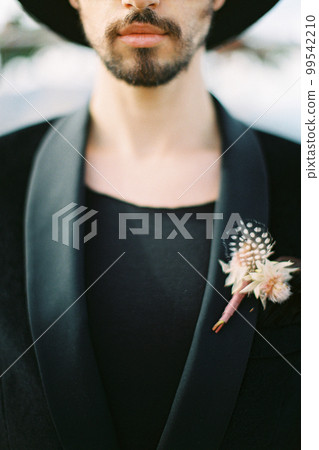 Boutonniere is pinned to the groom jacket. Close-up 99542210