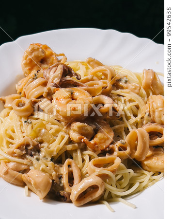 Shrimps in sauce lie on pasta in a plate 99542638