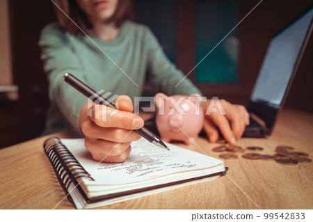Girl is making calculations, puts savings in a piggy bank. Girl is making calculations, puts savings in a piggy bank. 99542833