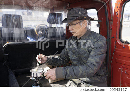 Gray-haired senior man camping in a classic car 99543117
