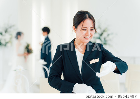 Wedding planner, bridesmaid, attendant, hotelier woman looking at watch at wedding hall/hotel Wedding planner, bridesmaid, attendant, hotelier woman looking at watch at wedding hall/hotel 99543497