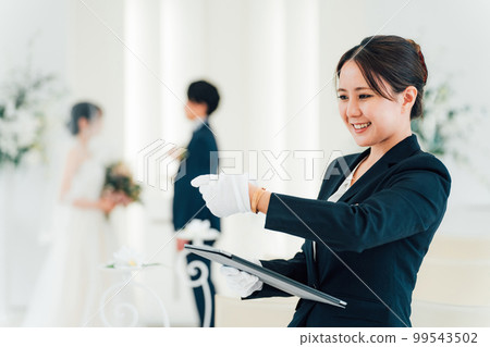 Wedding planner, bridesmaid, attendant, hotelier woman looking at watch at wedding hall/hotel Wedding planner, bridesmaid, attendant, hotelier woman looking at watch at wedding hall/hotel 99543502