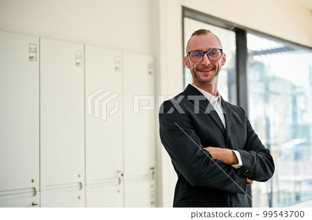 Caucasian businessman in formal business black suit stands with arms crossed in the office 99543700
