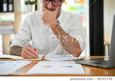 Cropped image of a thoughtful Caucasian businessman working on financial data report 99543749