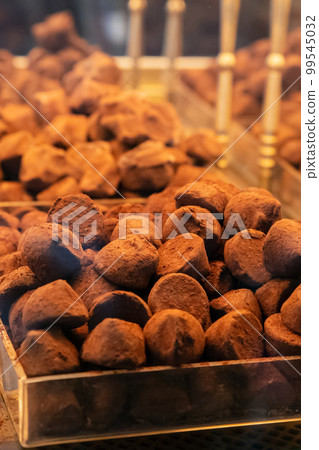 Chocolate truffles bites covered with cocoa a lot on shop window. Heap of chocolate truffle. Vertical photo Chocolate truffles bites covered with cocoa a lot on shop window. Heap of chocolate truffle. Vertical photo 99545032