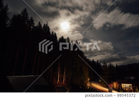 Night image of the sky with dense layers of clouds and the moon. 99545372
