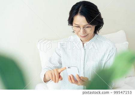 戴眼鏡的中年婦女看智能手機 99547153