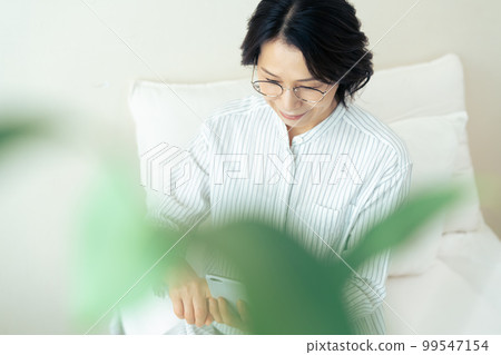 戴眼鏡的中年婦女看智能手機 99547154