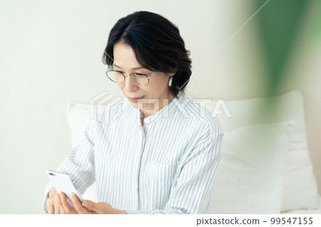 Middle woman wearing glasses looking at smartphone 99547155