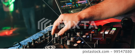 hands of a DJ in a booth playing on the mixer 99547880
