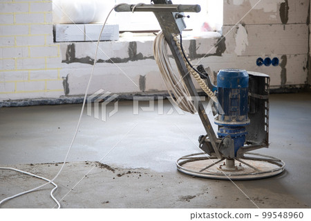 Ramming and grinding of semi-dry floor screed by a machine with a rotating disk for leveling. Construction of a concrete floor in the house, a master with special equipment. 99548960