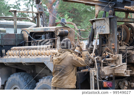 Team of workers with drilling rig on car are drilling artesian well for water in ground. Insertion of metal casing pipe into ground, installation of individual drinking supply, June 28, 2022, Russia, Team of workers with drilling rig on car are drilling artesian well for water in ground. Insertion of metal casing pipe into ground, installation of individual drinking supply, June 28, 2022, Russia, 99549027