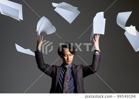 一個年輕人表情嚴肅地扔紙忙碌加班放棄商業形象 99549104