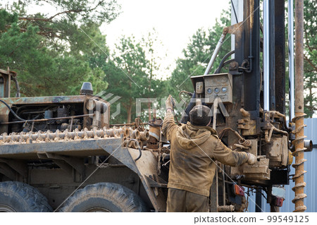 Team of workers with drilling rig on car are drilling artesian well for water in ground. Insertion of metal casing pipe into ground, installation of individual drinking supply, June 28, 2022, Russia, Team of workers with drilling rig on car are drilling artesian well for water in ground. Insertion of metal casing pipe into ground, installation of individual drinking supply, June 28, 2022, Russia, 99549125