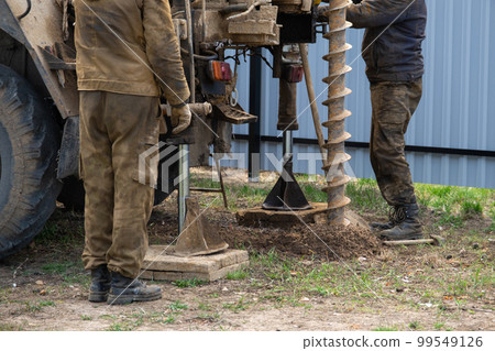 Team of workers with drilling rig on car are drilling artesian well for water in ground. Insertion of metal casing pipe into ground, installation of individual drinking supply, June 28, 2022, Russia, 99549126