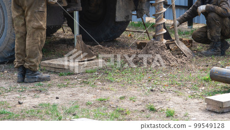 Team of workers with drilling rig on car are drilling artesian well for water in ground. Insertion of metal casing pipe into ground, installation of individual drinking supply, June 28, 2022, Russia, Team of workers with drilling rig on car are drilling artesian well for water in ground. Insertion of metal casing pipe into ground, installation of individual drinking supply, June 28, 2022, Russia, 99549128