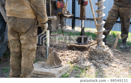 Team of workers with drilling rig on car are drilling artesian well for water in ground. Insertion of metal casing pipe into ground, installation of individual drinking supply, June 28, 2022, Russia, 99549131