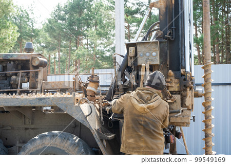 Team of workers with drilling rig on car are drilling artesian well for water in ground. Insertion of metal casing pipe into ground, installation of individual drinking supply, June 28, 2022, Russia, Team of workers with drilling rig on car are drilling artesian well for water in ground. Insertion of metal casing pipe into ground, installation of individual drinking supply, June 28, 2022, Russia, 99549169