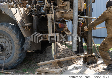 Team of workers with drilling rig on car are drilling artesian well for water in ground. Insertion of metal casing pipe into ground, installation of individual drinking supply, June 28, 2022, Russia, 99549174