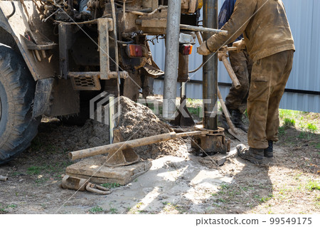 Team of workers with drilling rig on car are drilling artesian well for water in ground. Insertion of metal casing pipe into ground, installation of individual drinking supply, June 28, 2022, Russia, 99549175