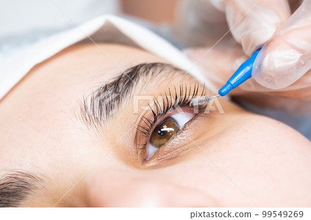 The master combs the eyelashes of the client after the lamination procedure. The master combs the eyelashes of the client after the lamination procedure. 99549269