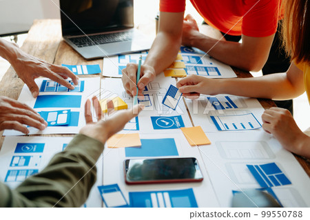 UX developer and ui designer brainstorming about mobile app interface wireframe design with customer breif and color code at modern office.. UX developer and ui designer brainstorming about mobile app interface wireframe design with customer breif and color code at modern office.. 99550788