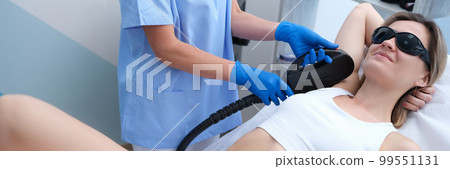 Young woman undergoes armpit laser hair removal treatment at beauty spa 99551131