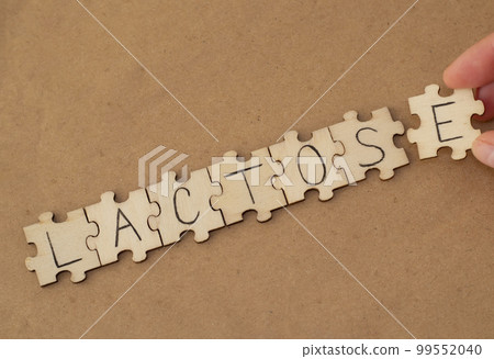 The word written on the wooden puzzles lettering is Lactose. A woman is putting a puzzle together. 99552040
