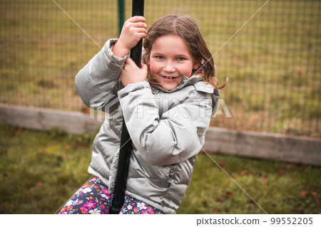 Cute girl having fun at the playground. Happy girl in glasses swings. Autumn Cute girl having fun at the playground. Happy girl in glasses swings. Autumn 99552205