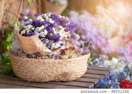Violet flowers in a straw basket on a wooden table outdoors 99552288